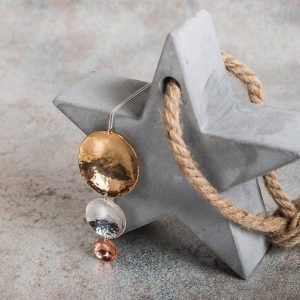 A hand made pendant necklace with 3 hammered discs in decreasing sizes in brass, copper and silver.