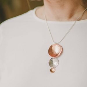 A hand made pendant necklace with 3 hammered discs in decreasing sizes in brass, copper and silver.