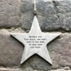 A grey ceramic rustic hanging star printed with the words Mothers are like stars you don't have to see them to know they are there.