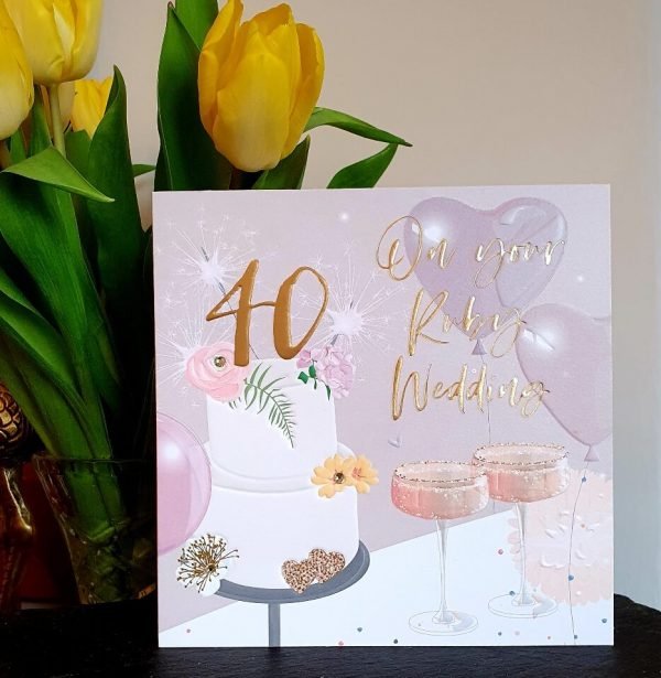 A large luxury 40th ruby wedding anniversary card with a cake and champagne glasses, embellished with clear crystal gem stones and gold foiled lettering with a large 40 on top of the cake and the words On Your Ruby Wedding