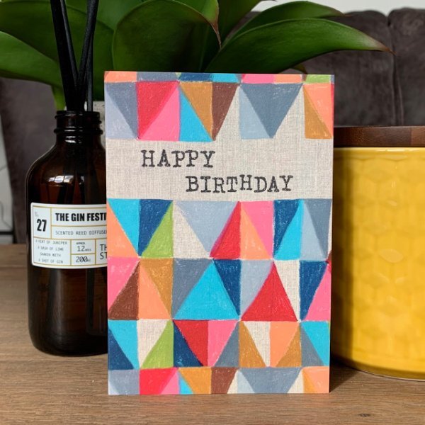 A colourful card with geometric shapes all over it in an assortment of colours and the words Happy Birthday printed on it.