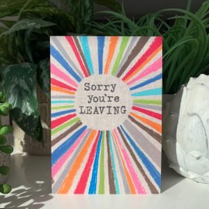 A multi coloured rainbow card with the words Sorry You're Leaving printed in the centre of it.