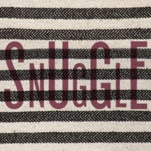 a long cushion with the word Snuggle printed in burgundy over navy and white heavy cotton ticking fabric