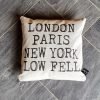 A hand made square cushion with a feather filled inner and a natural linen cover that is printed with London Paris New York Low Fell