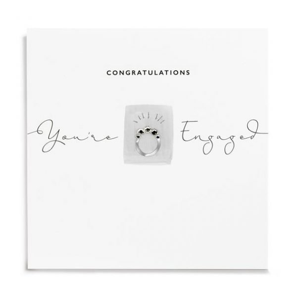 A white square card with a little rectangle which has an image of an engagement ring on it which has been finished with diamante. The words Congratulations You're Engaged areprinted on the card.
