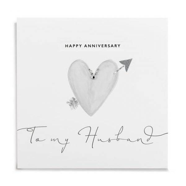 A white square card with a grey heart with an arrow through it which is finished off with little diamante on it. The Words Happy Anniversary to my husband is also printed on it.
