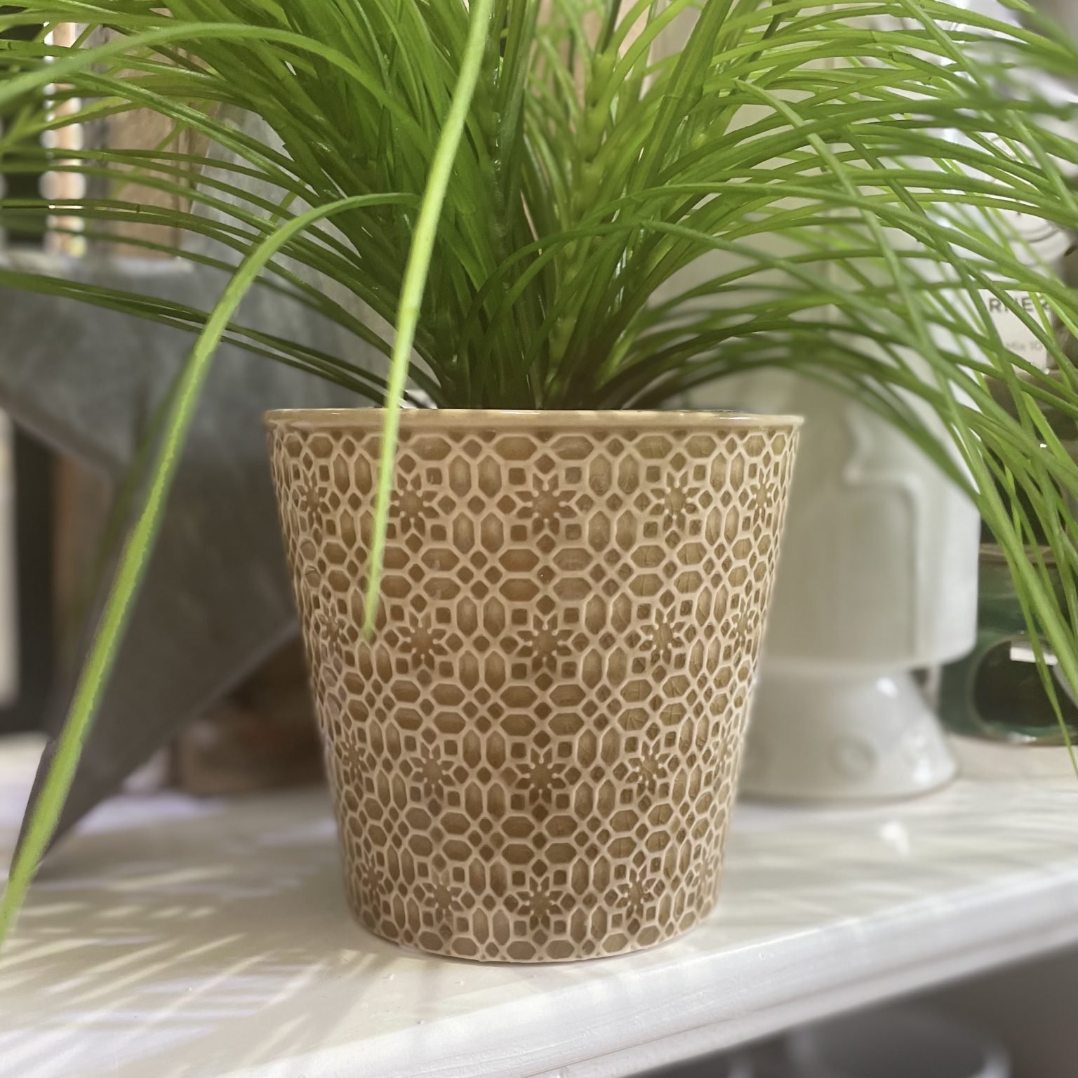 A stoneware planter with a mosaic pattern and a mustard glaze