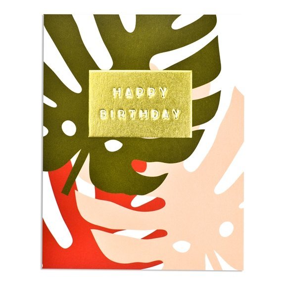 A birthday card with colourful big rubber plant leaves with a gold foiled panel with happy birthday embossed into it.