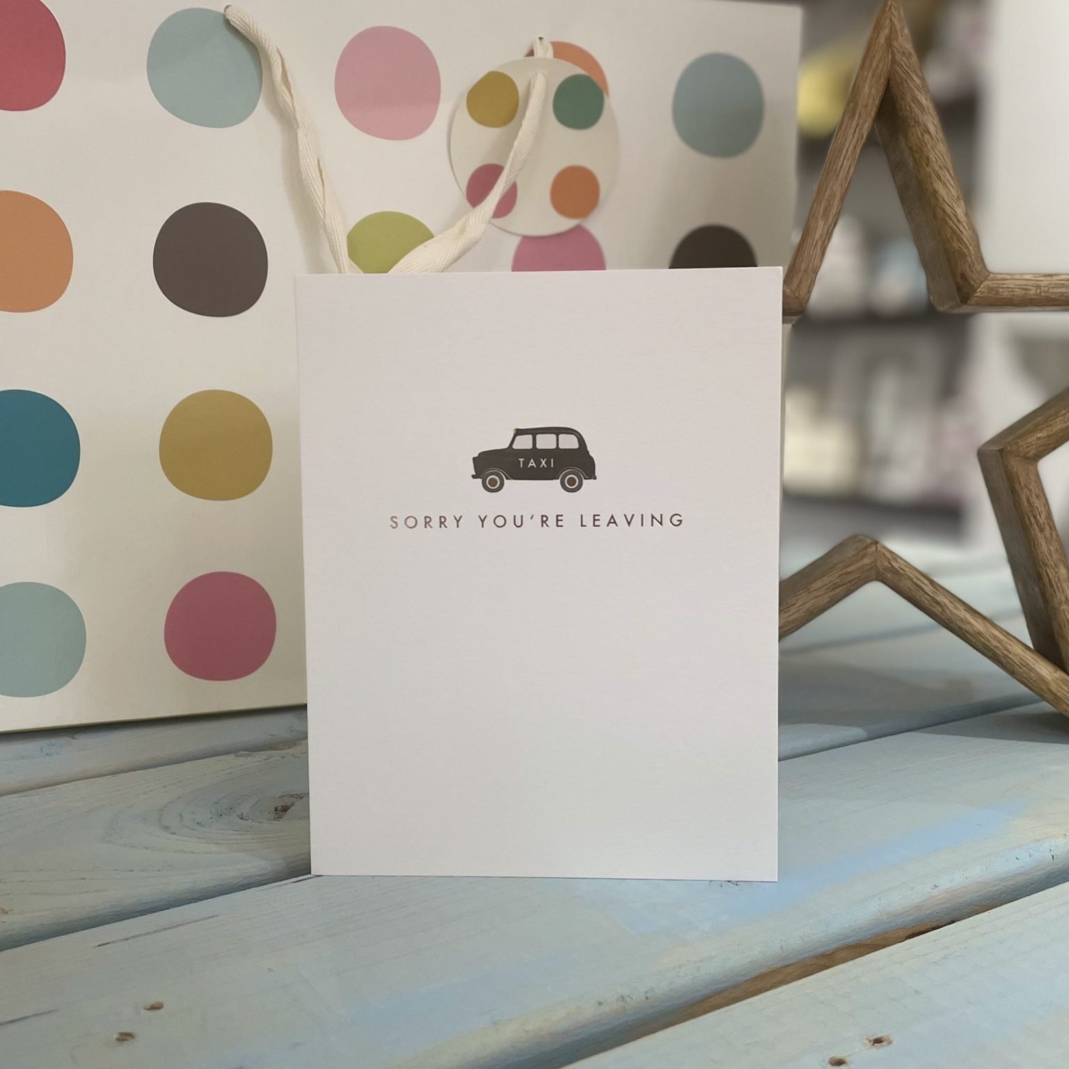 A white card with a little embossed taxi and the words sorry you're leaving underneath