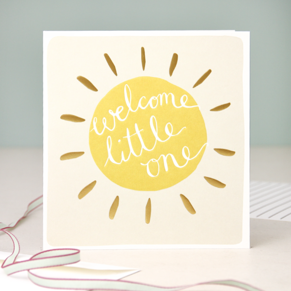 A neutral new baby card with a yellow and gold sun with welcome little one on the inside of the sun. blank inside