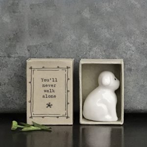 A sweet little ceramic dog keepsake in a little matchbox with the words You'll never walk alone' printed on it