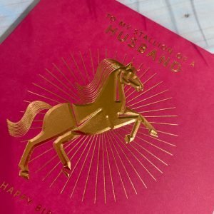 A red square card with a goild foil image of a horse on it and the words To My stallion of a husband printed on it.