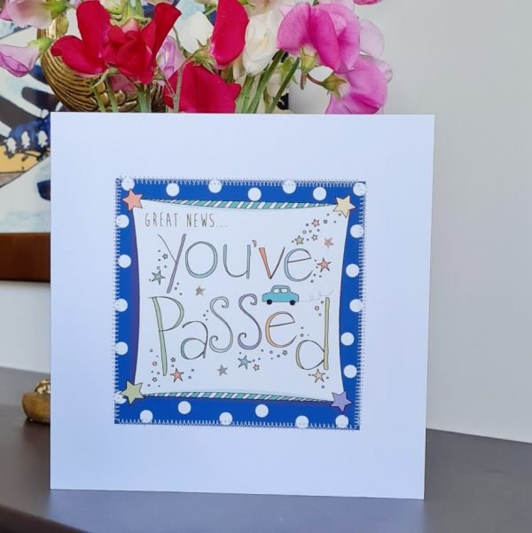 A card to congratulate You've passed your driving test card. A white card with a square of navy blue polka dot paper stitched on to it with a further white square with a hand illustration of the words You've Passed decorated with a little blue car and hand drawn stars. Great news You've Passed