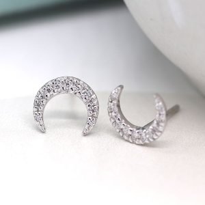 A pair of crescent moon stud earrings with cubic zirconia crystal effect.