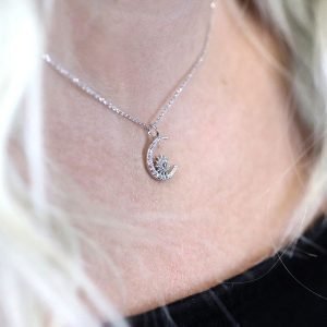 A beautiful moon and starburst charm necklace which is covered in cubic zirconia crystals on a 16 inch silver chain.