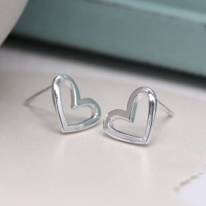 A pair of smooth asymmetric cut out heart stud earrings made from sterling silver.