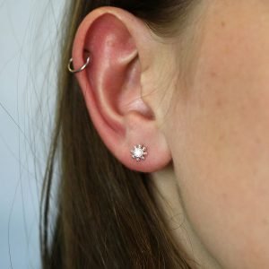 A lovely pair of flower style stud earrings with a faceted cubic zirconia centre and fancy edging made from sterling silver.