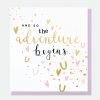 A wedding card with gold foil horeshoes and hearts and the words and so the adventure begins