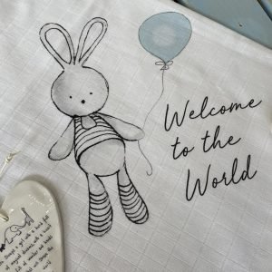 A cute blue bunny welcome muslin cloth with a design of a bunny holding a blue balloon with the words Welcome to the World on it.