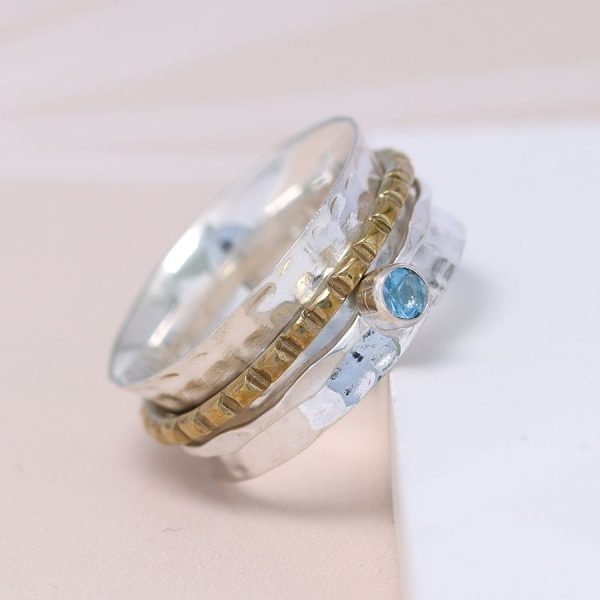 A hammered sterling silver ring with a textured brass band and a fine silver band set with a beautiful blue topaz