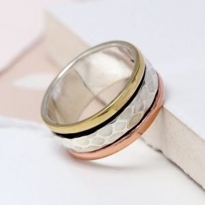 A sterling silver ring with three bands of different metallic finish, black, rose gold and gold and a central silver spinning band