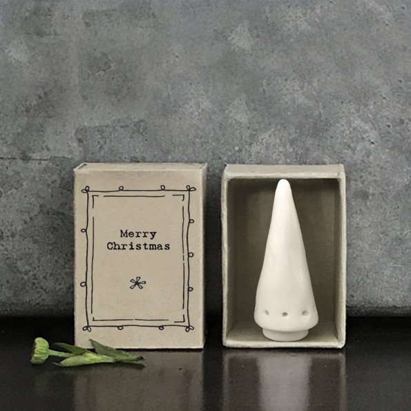 A small white porcelain Christmas tree in a box the size of a matchbox that says Merry Christmas on the front