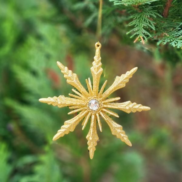 A gold starburst Christmas decoration. Gold glitter starburst with a large clear crystal in the centre