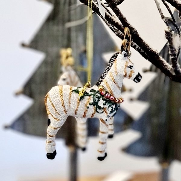 An embellished Zebra decoration with a feather crown and a garland of crystals. The resin zebra decoration has gold glitter stripes and can either hang from the tree or stand