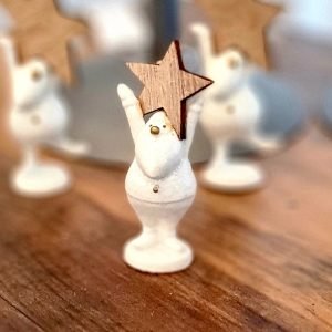 A tiny white resin santa holding a wooden star standing