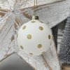 A white glass bauble with gold glitter spots all over it