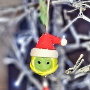 A hanging ceramic sprout with cute eyes and a santa hat