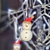 A white ceramic hanging snowman with a red hat with gold glitter pom pom and trim