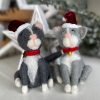 A pair of Christmas cats made from felt and wearing santa hats and red collars.