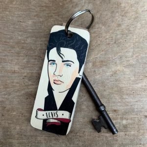 A wooden key ring with an illustration of Elvis Presley in a caricature style