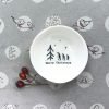 A sweet little ceramic wobbly bowl with an image of Christmas trees and with the words Merry Christmas printed on it.
