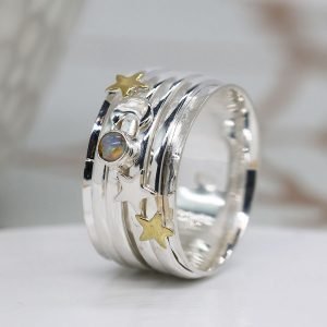 A moon and Star ring with additional spinning rings around it. There are gemstones and stars on the additional rings.