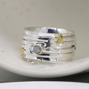 A moon and Star ring with additional spinning rings around it. There are gemstones and stars on the additional rings.