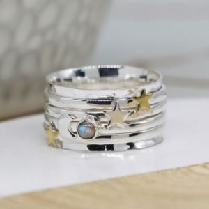 A moon and Star ring with additional spinning rings around it. There are gemstones and stars on the additional rings.