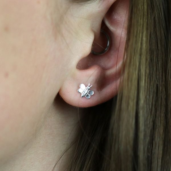 A pair of sterling silver stuff earrings that are shaped like tiny bumblebees.