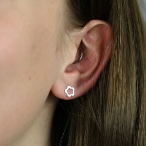 A pair of sterling silver stud earrings with a cutout flower design