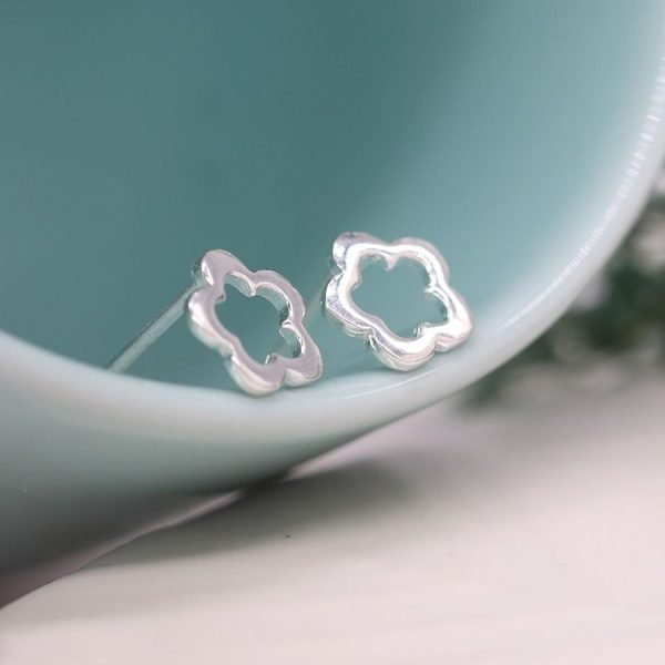 A pair of sterling silver stud earrings with a cutout flower design