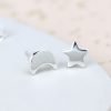 A pair of sterling silver stud earrings that have one with a moon shape and the other a star shape.