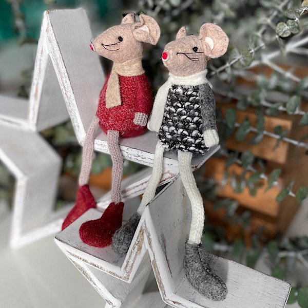 A pair of cute sitting mice. One has a red jumper and beige scarf and the other has a black and white patterned jumper and a white scarf. Both have dangly legs.