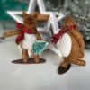 A pair of snow boarding bears made from felt. One is snowbaording with a leg in the air and the other is holding a christmas tree,