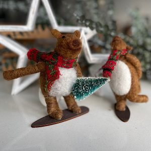 A pair of snow boarding bears made from felt. One is snowbaording with a leg in the air and the other is holding a christmas tree,