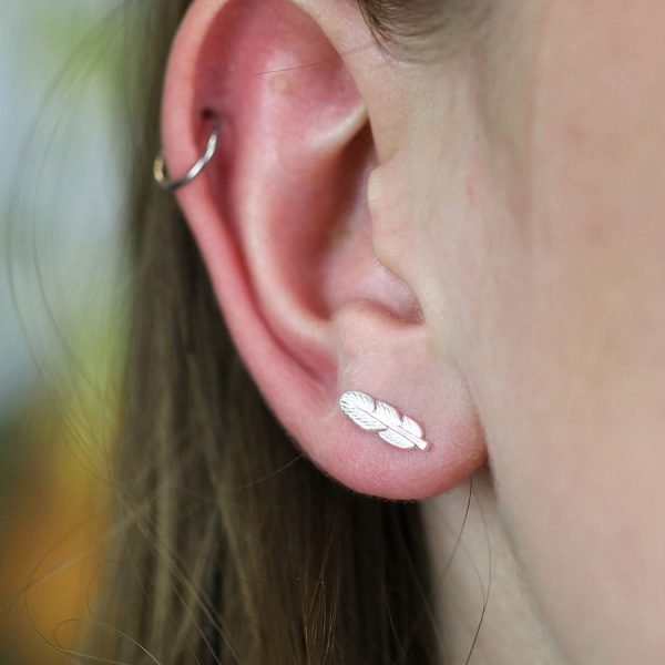 A pair of tiny sterling silver feather stud earrings