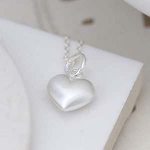 A silver chain necklace with a heart pendant in a smooth satin finish