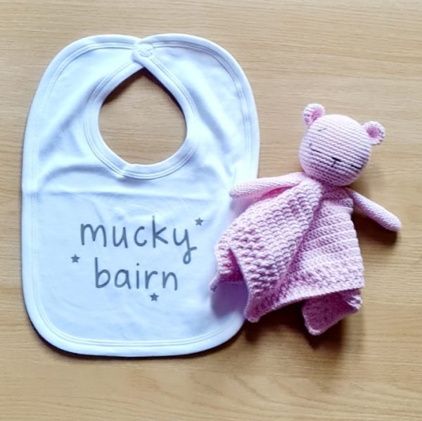 A white cotton bib printed in grey with mucky bairn