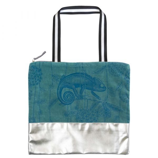 A shopper bag with a teal velvet panel with a chameleon design and silver faux leather bottom and back. Coral sateen lining and zip top
