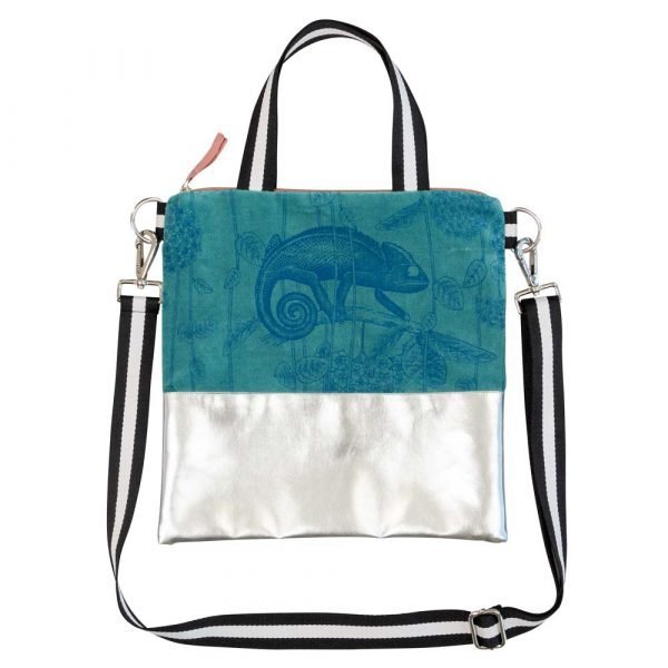 A teal velvet and silver faux leather cross over hand bag. The teal velvet is printed with a chameleon design. The strap is detachable and the lining is peach sateen.